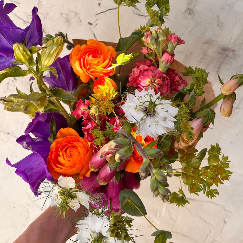 Orange ranunculus and purple bellflower bouquet